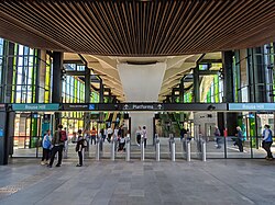 Tallawong Metro Station entrance with timber-clad canopy, glass facade and commuters passing through ticket gates